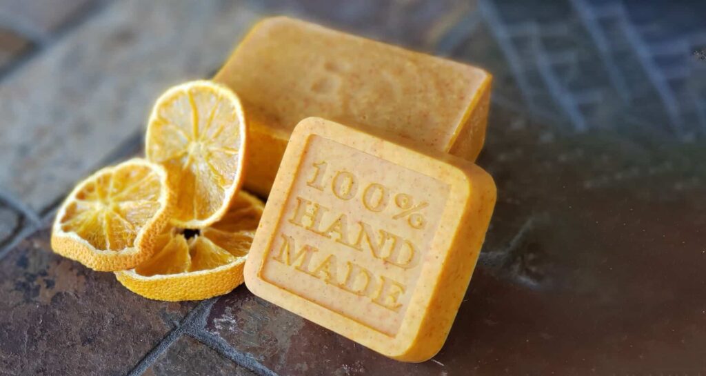 Homesteading from your apartment: Two bars of 100% handmade soap with a lemon wheel beside it. 