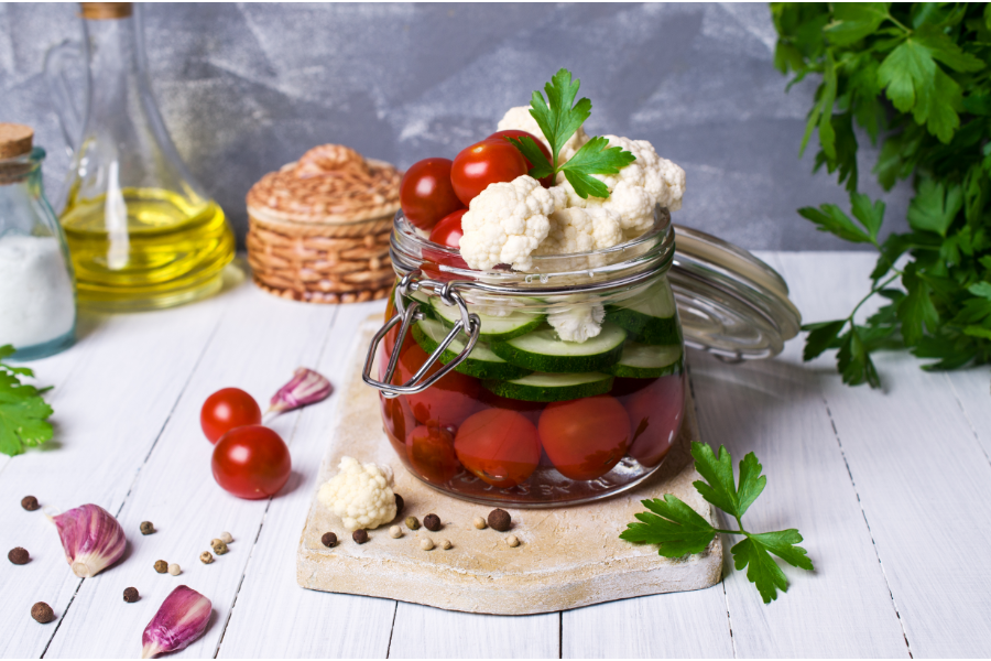 A jar with cauliflower, tomatoes and cucumbers ready for quick pickling. 