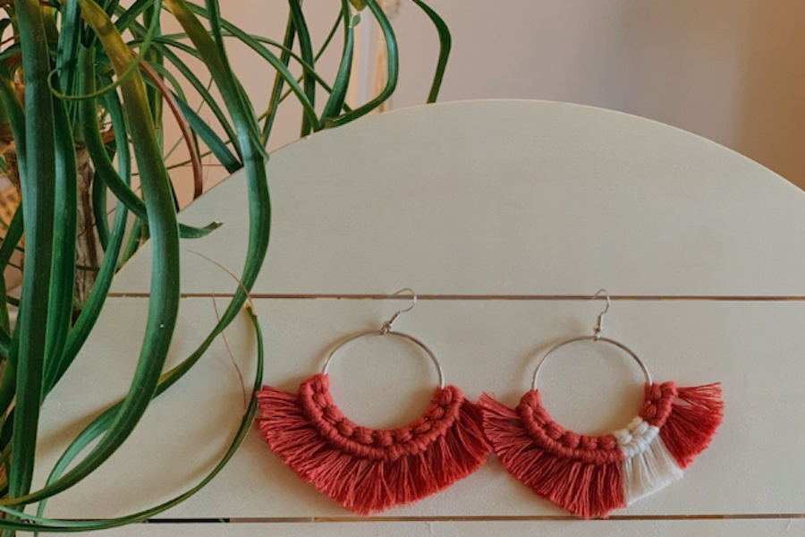 Pair of orange and white handmade macrame earrings. 