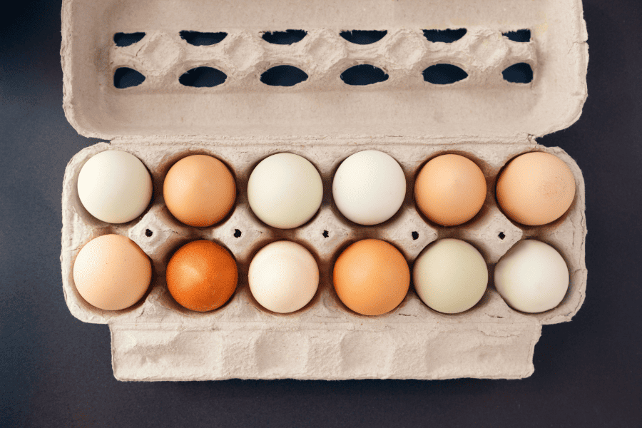 Assorted coloured eggs in an open carton. 