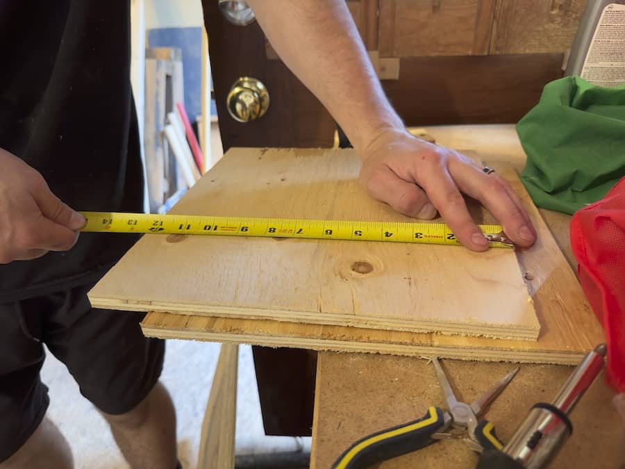 Arthur measuring out plywood to build nesting boxes with using a measuring tape. 
