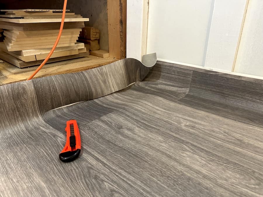 Cutting the linoleum flooring with an exacto knife. 