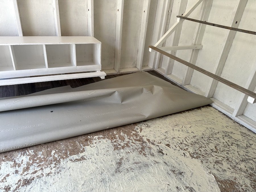 One side of the chicken coop covered in adhesive before laying down the linoleum flooring.