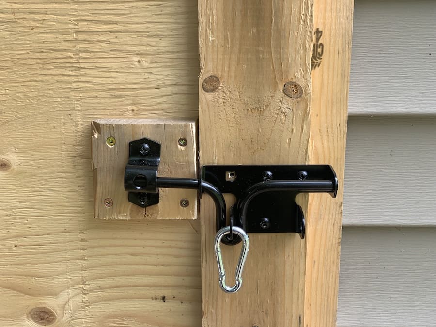 close up of the carabiner on the lock to keep predators out of the chicken coop. 