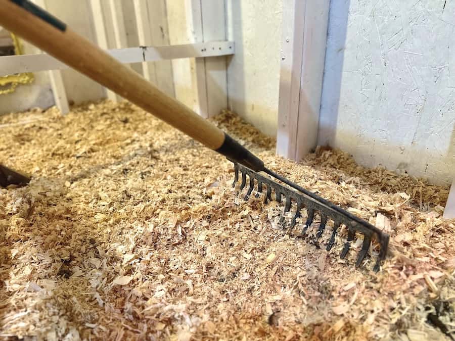 A rake scooping and mixing chicken bedding and manure