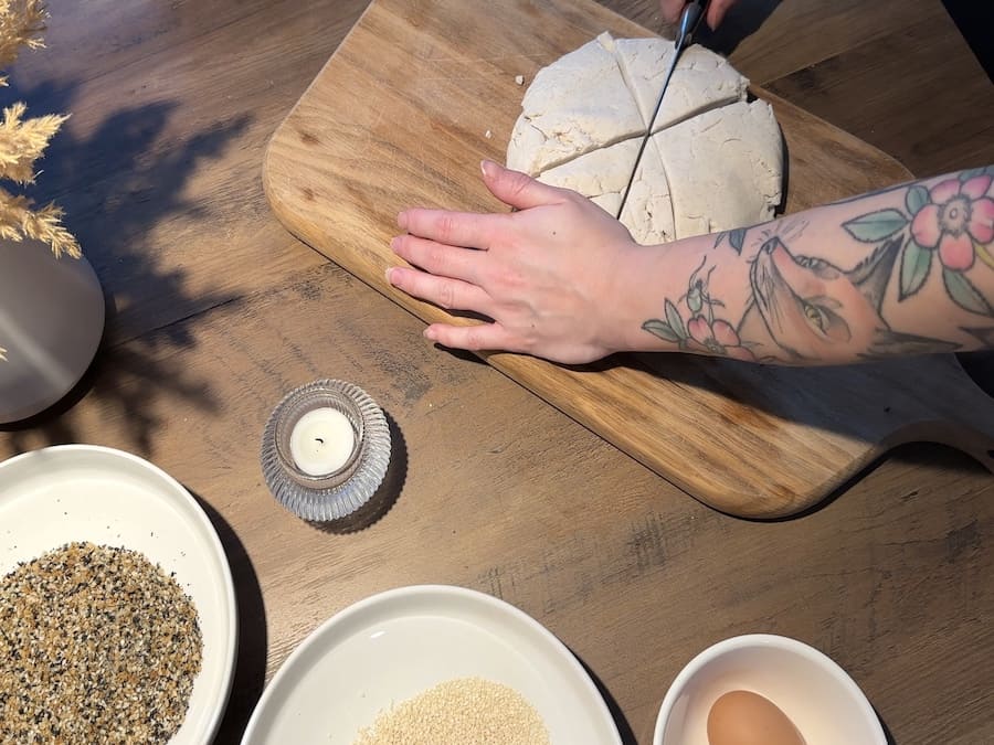 Julia cutting homemade dough that she made from scratch with a knife on a wooden cutting board.