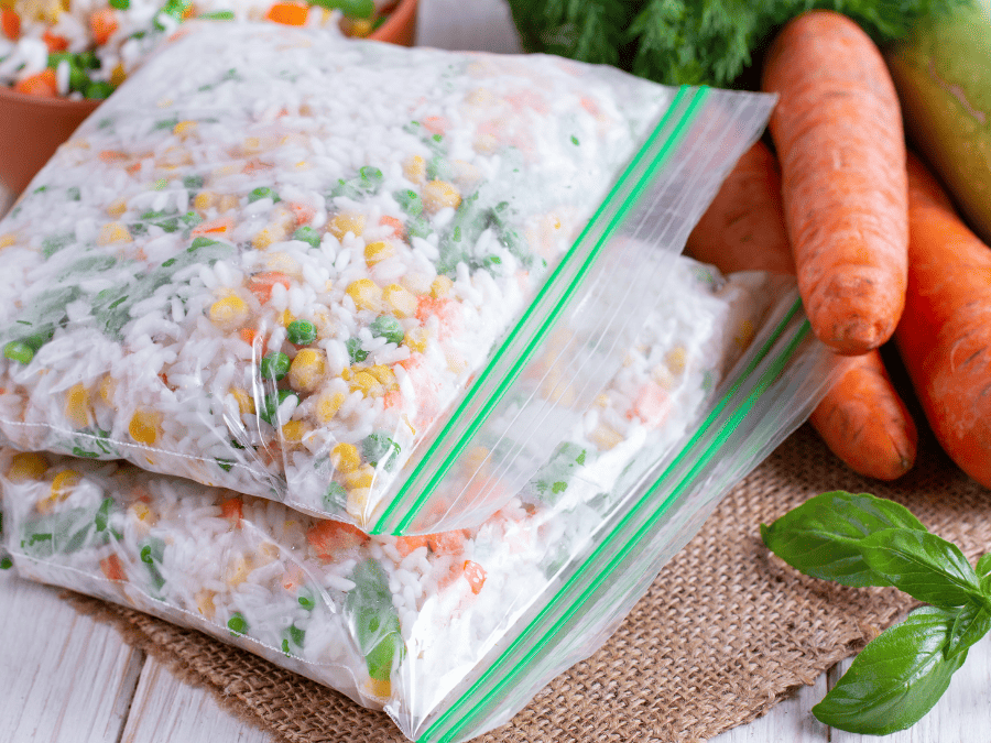 Two freezer zip lock bags full of a rice and vegetable medley waiting to go in the freezer.