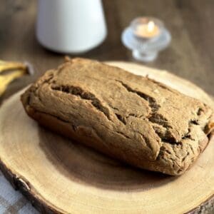 A loaf of gluten-free banana bread on a wooden plate.