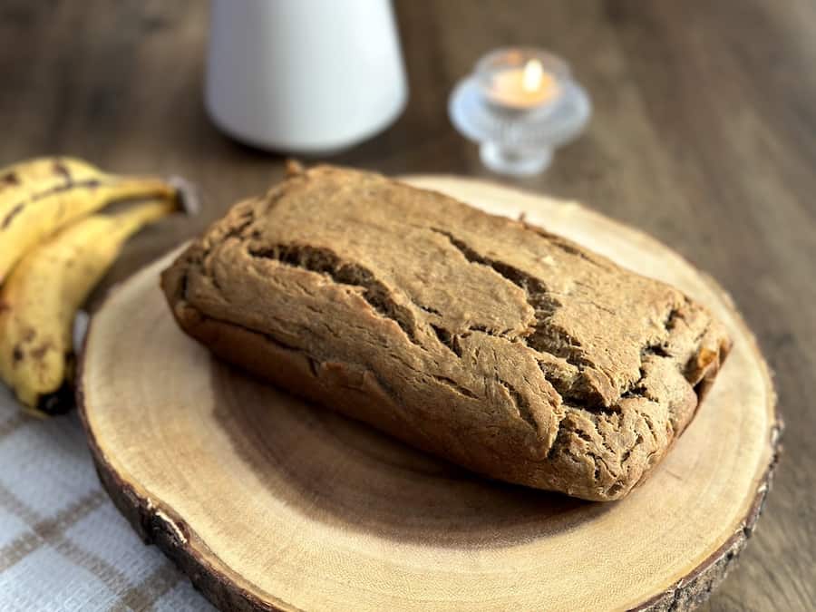 A loaf of gluten-free banana bread on a wooden plate.