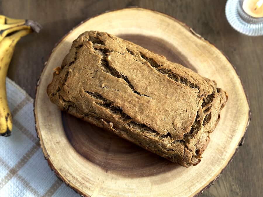 A loaf of gluten-free banana bread on a wooden plate.