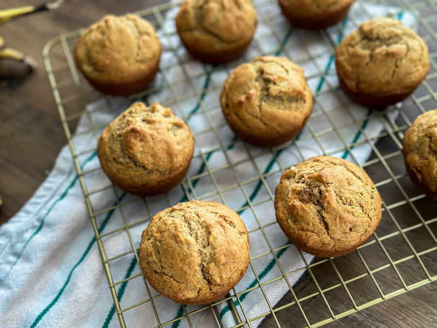 Nine Gluten-Free Banana Bread Muffin on a gold cooling rack with a striped tea cloth underneath. 