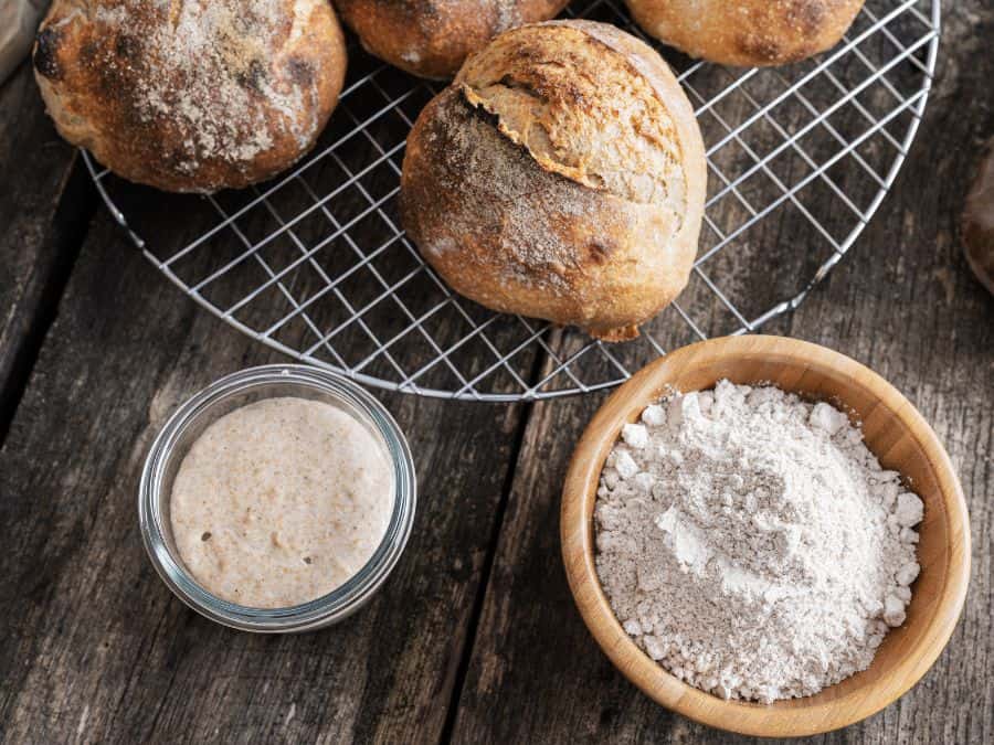 Sourdough starter, a bowl of flour and sourdough bread.