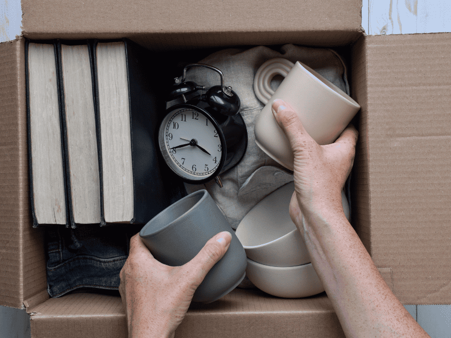 A hand packing away items into a box to donate