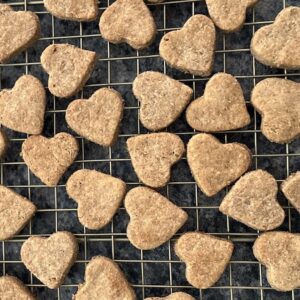 Homemade Dog treats shaped like hearts on a gold wire cooling rack.