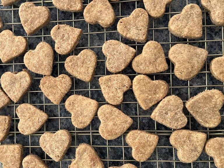 Homemade Dog treats shaped like hearts on a gold wire cooling rack.