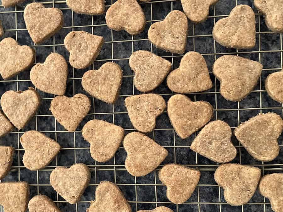 Homemade Dog treats shaped like hearts on a gold wire cooling rack.