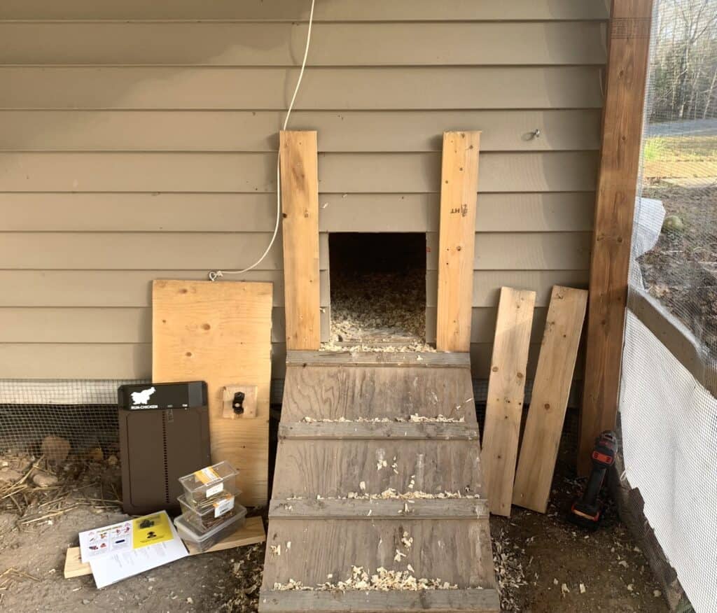 The external opening of our chicken coop where the old manual door used to be with the run-chicken automatic chicken coop door beside it, not yet installed.